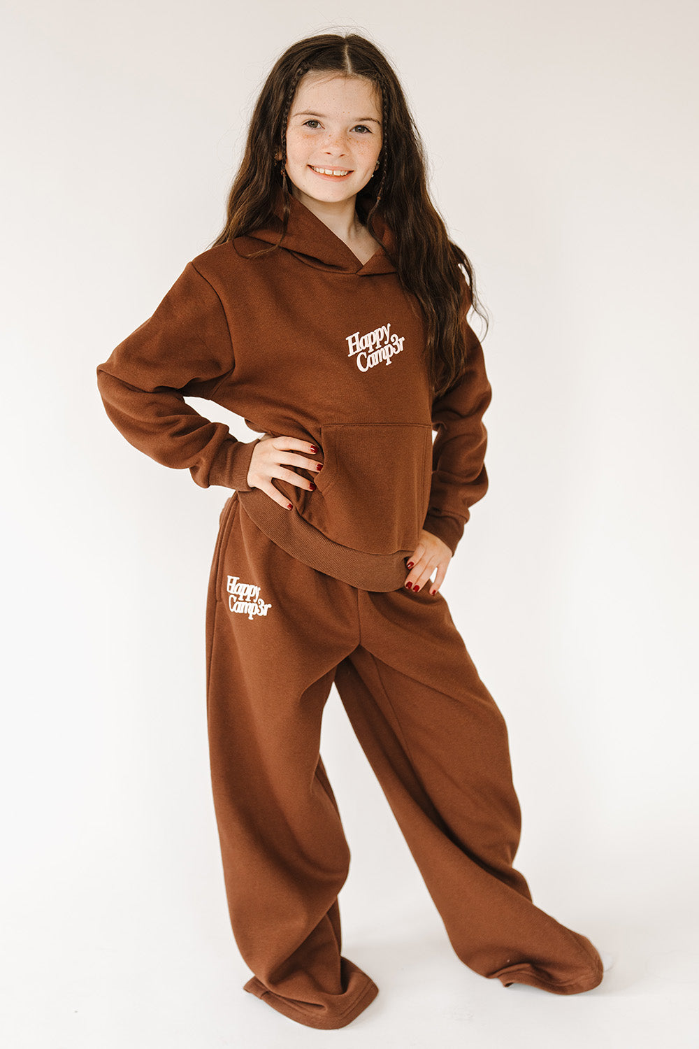 Girl in the espresso Puff Series Core Youth Hoodie and sweatpants, full length. The Happy Camp3r
