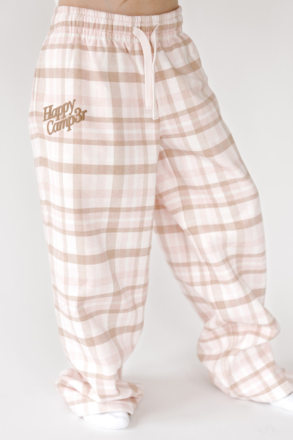 Pretty In Plaid Youth Sweatpants in pink and tan plaid with small logo, front view. The Happy Camp3r