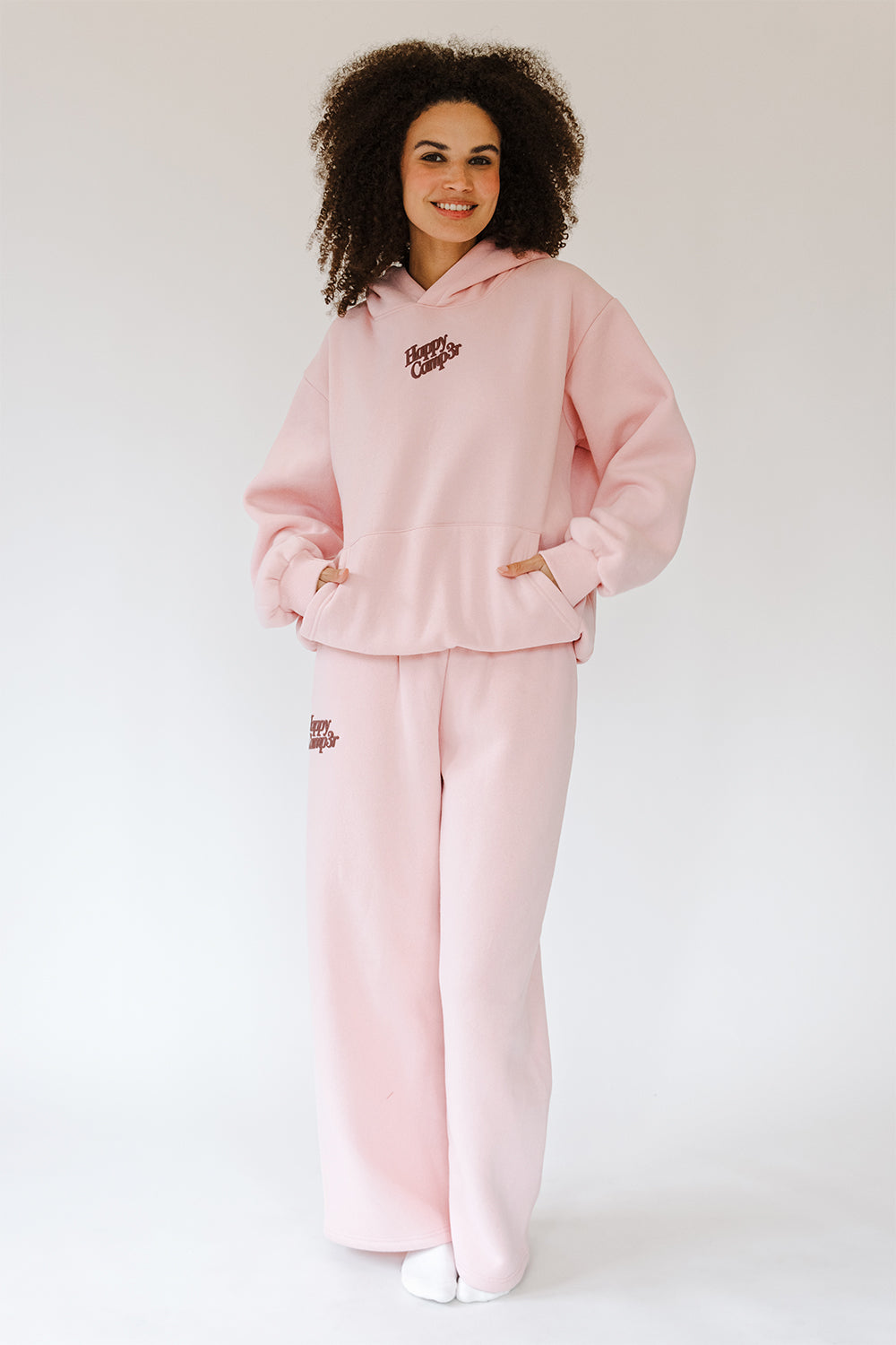 Model in the light pink Puff Series Hoodie and matching sweatpants, full length front view. The Happy Camp3r