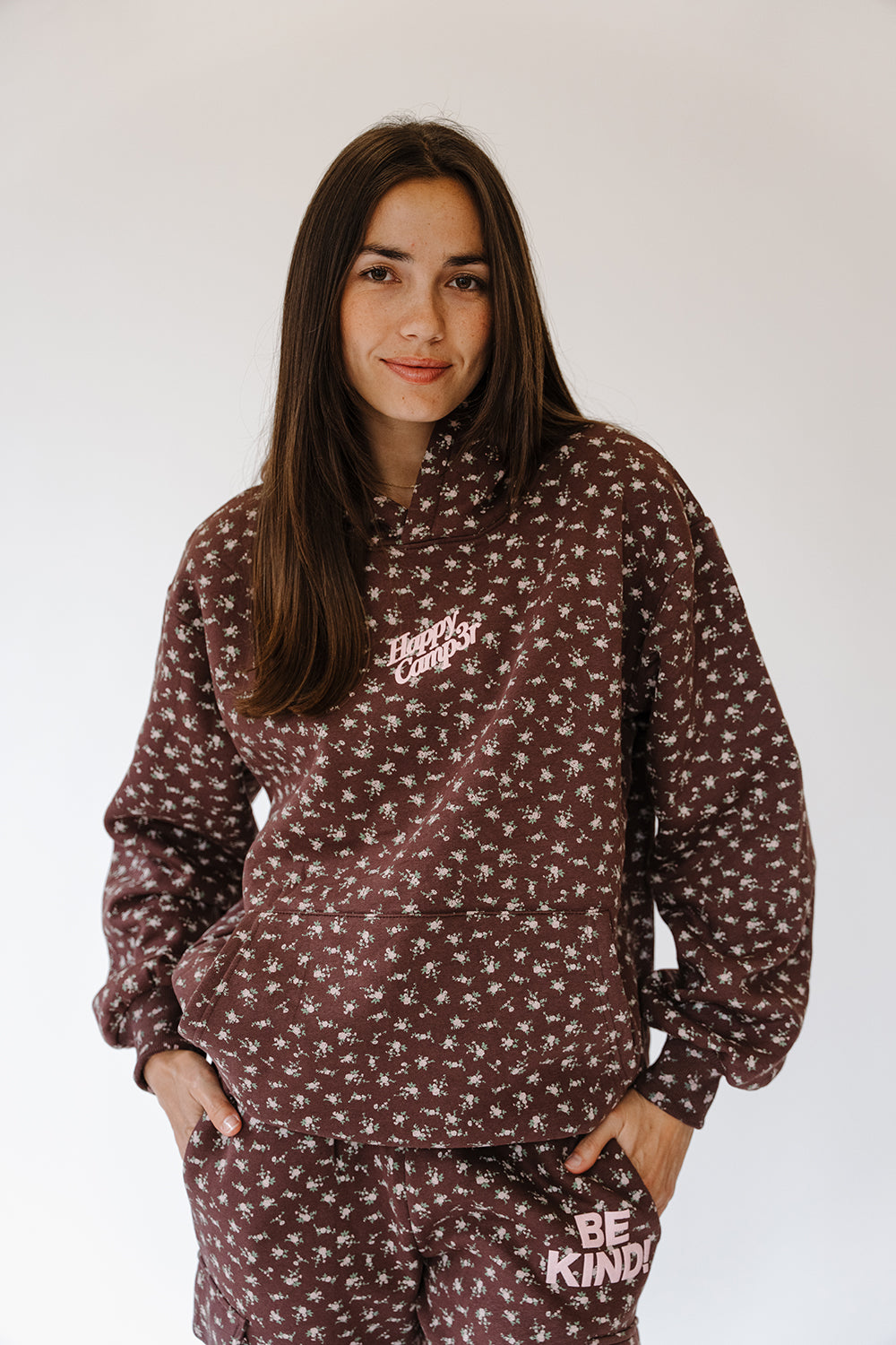 Be The Kind Hoodie in brown with tiny cream floral print and pink logo, front view. The Happy Camp3r