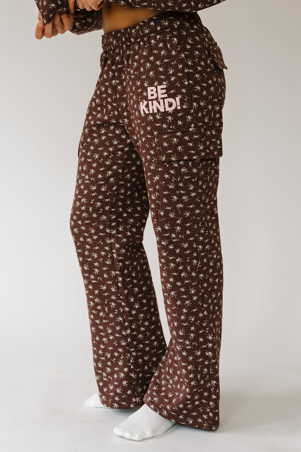 Be The Kind Cargo Sweatpants in brown floral print with Be Kind text, side view. The Happy Camp3r